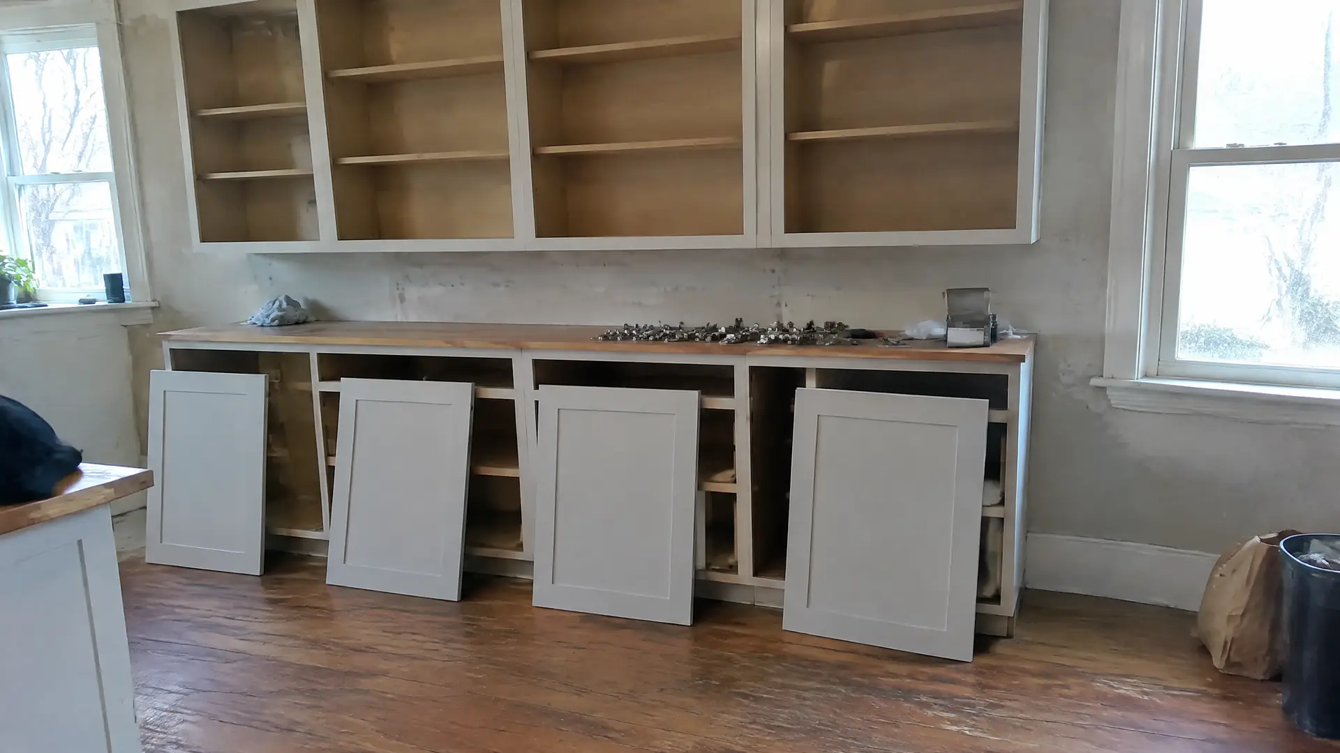 Bare cabinet face frames with new shaker doors leaning ready to hang during a door replacement in Lynn