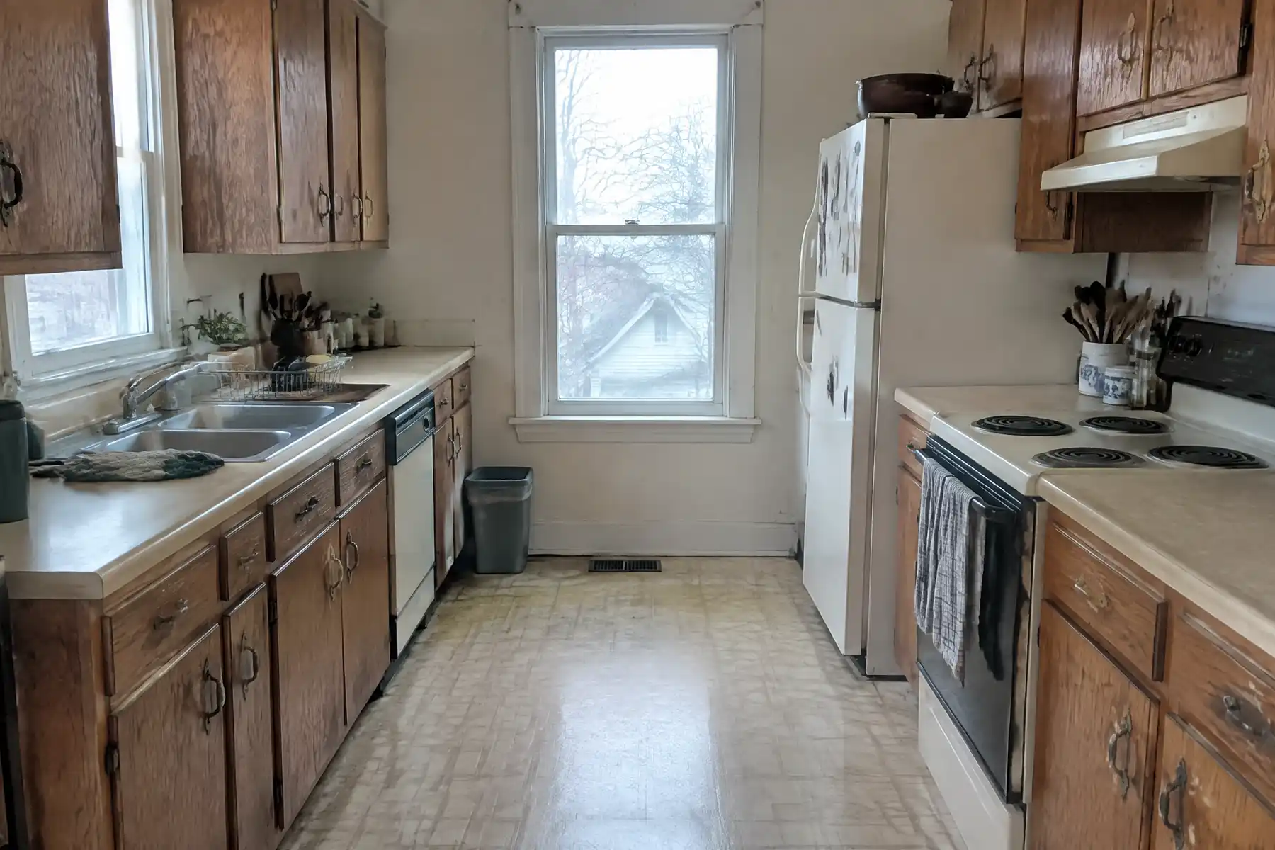 A dated galley kitchen with worn dark oak cabinets and laminate counters before refacing