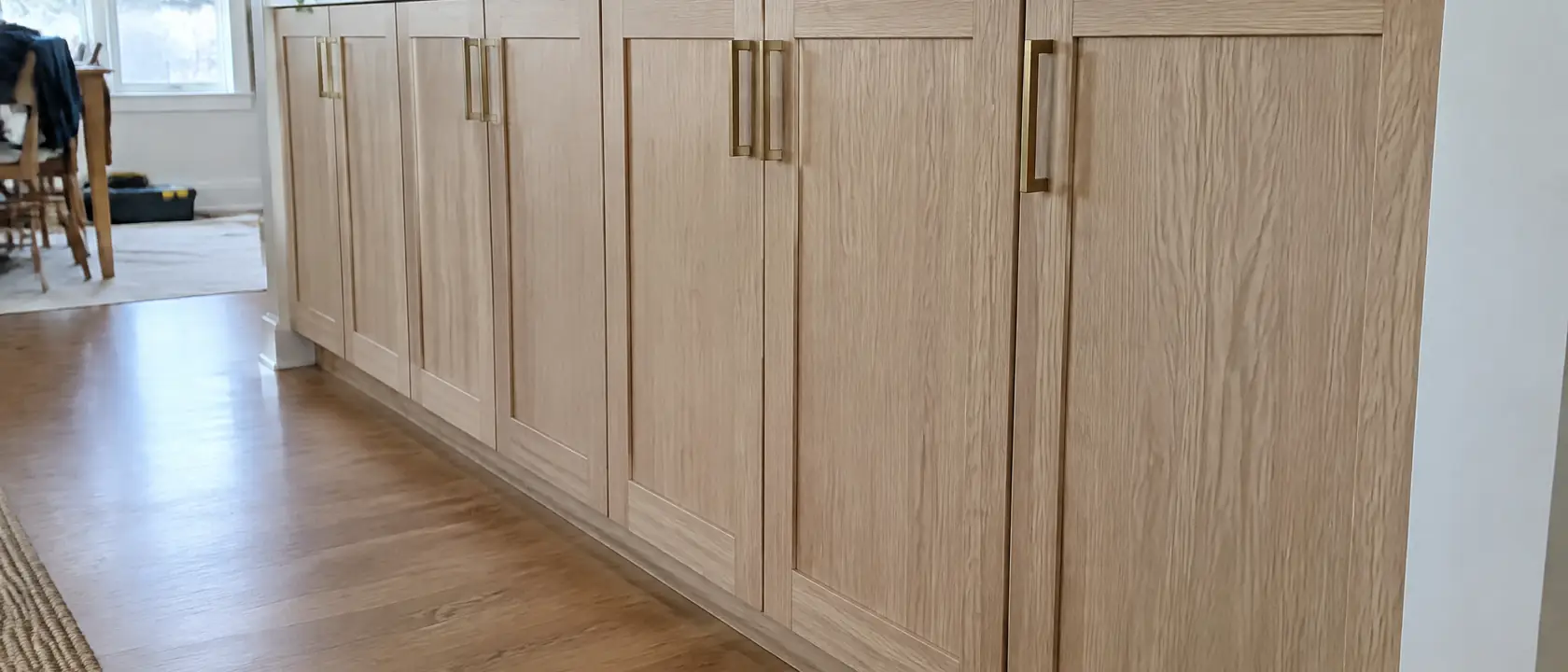 A run of refaced white oak cabinet doors with even reveals and aged brass pulls