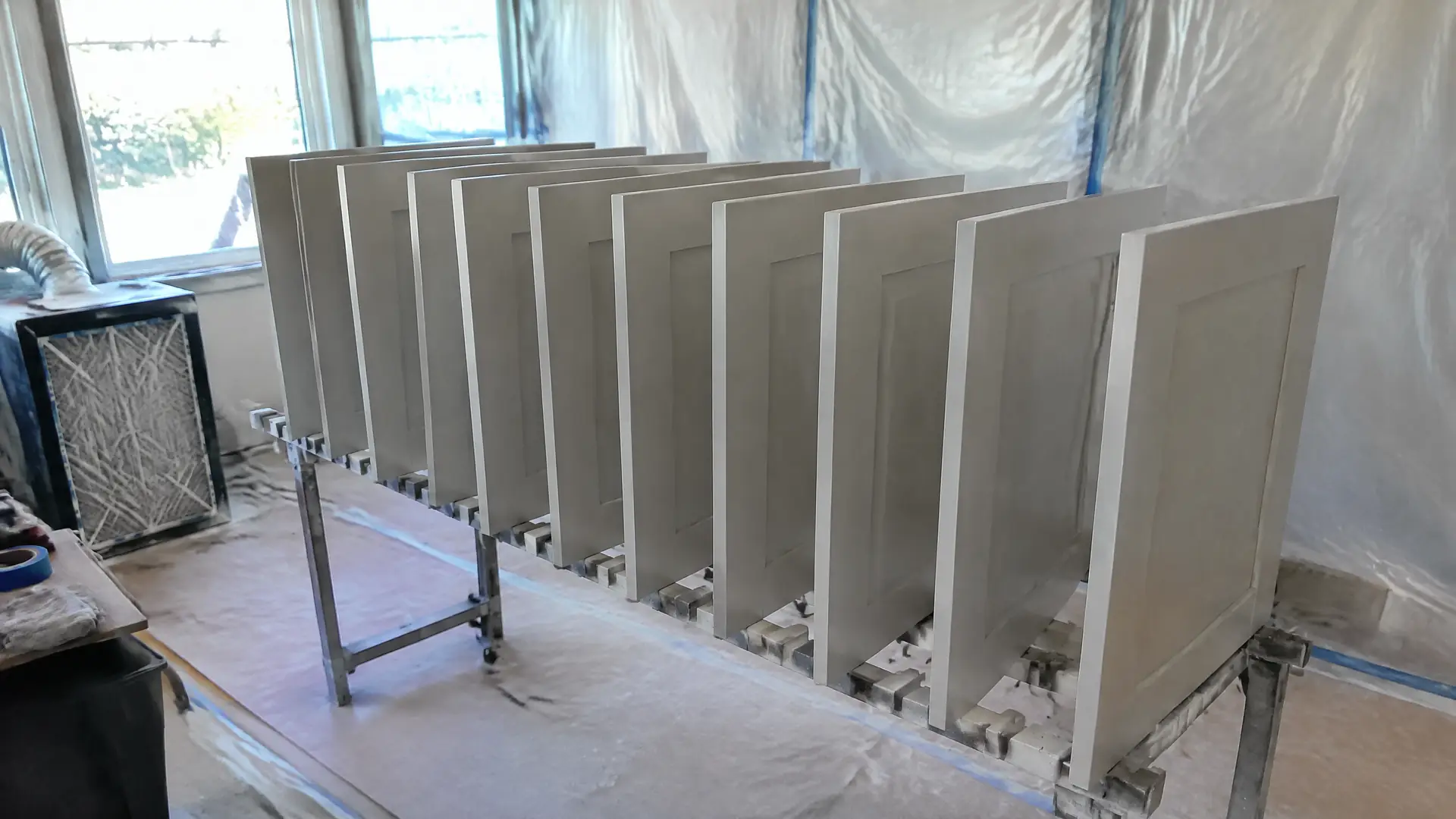 Freshly sprayed cabinet door fronts standing on edge in a finishing-room drying rack
