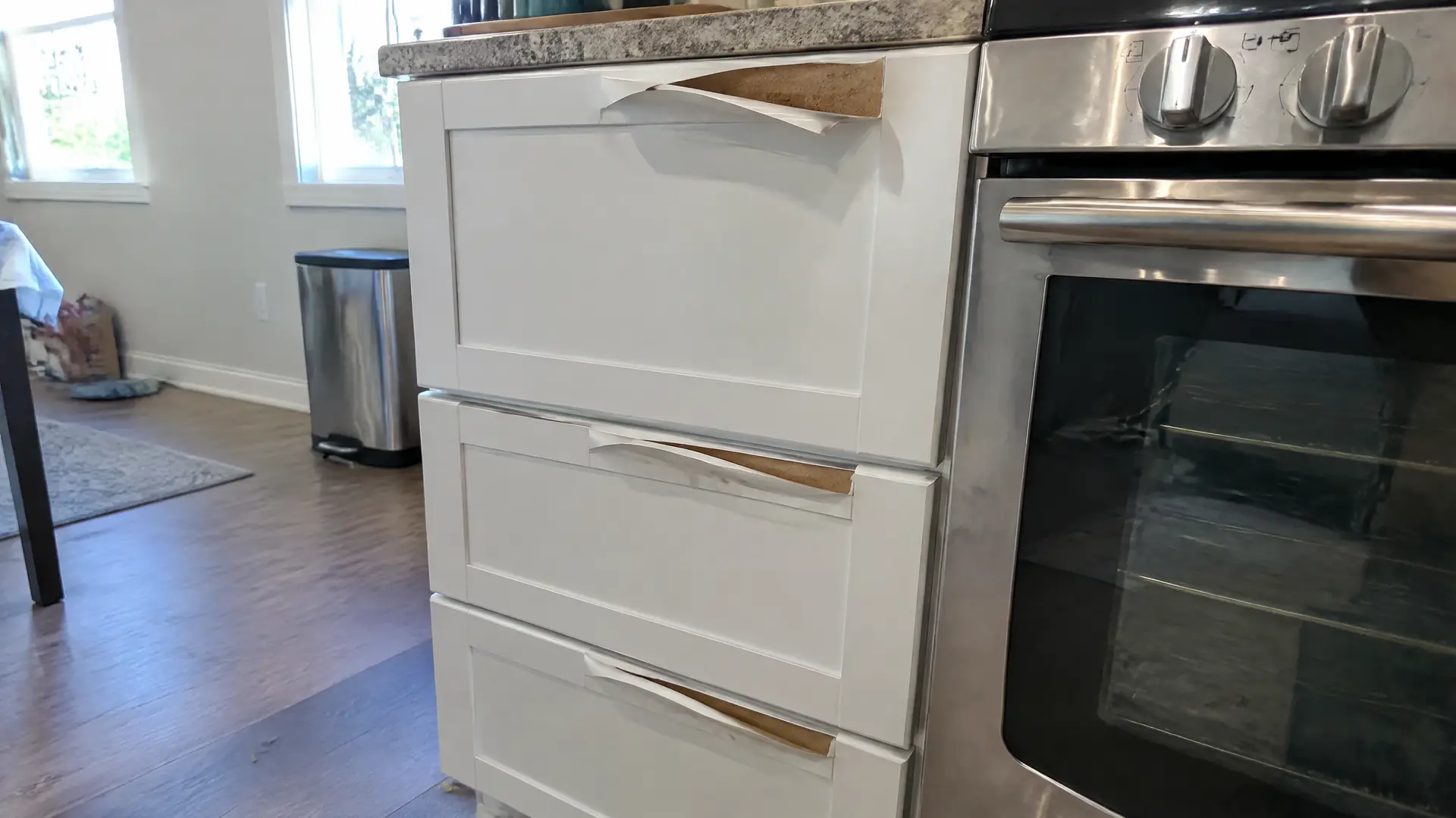 Thermofoil drawer fronts beside an oven with the film lifting and curling off the top edges