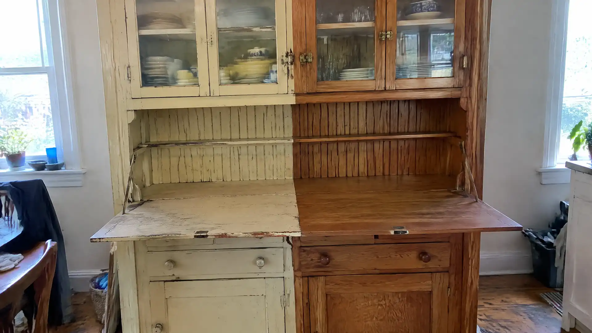 An early-1900s built-in kitchen dresser half stripped back to warm wood, half under old paint