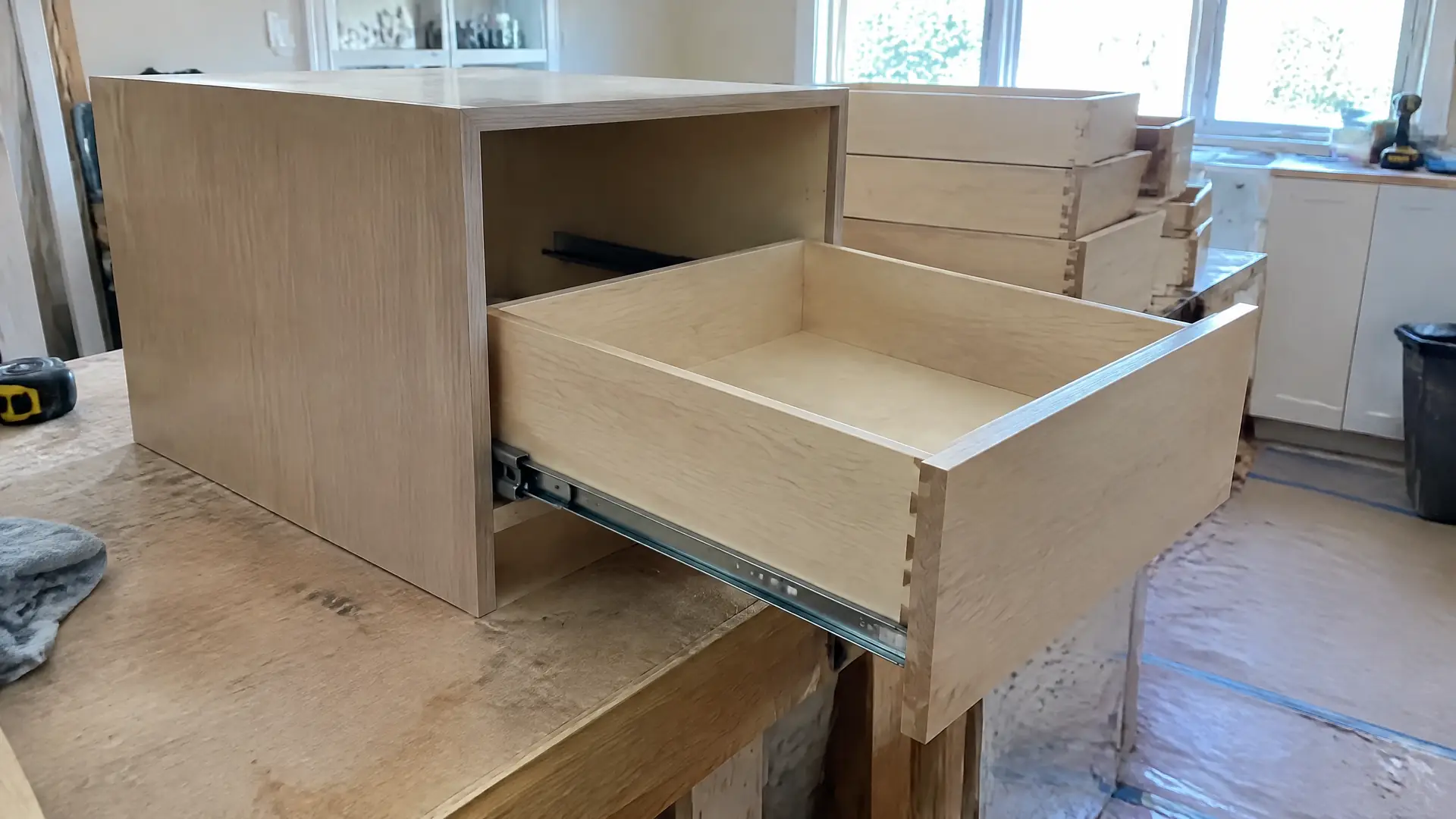 A plywood cabinet box with a dovetailed drawer pulled open on ball-bearing side slides