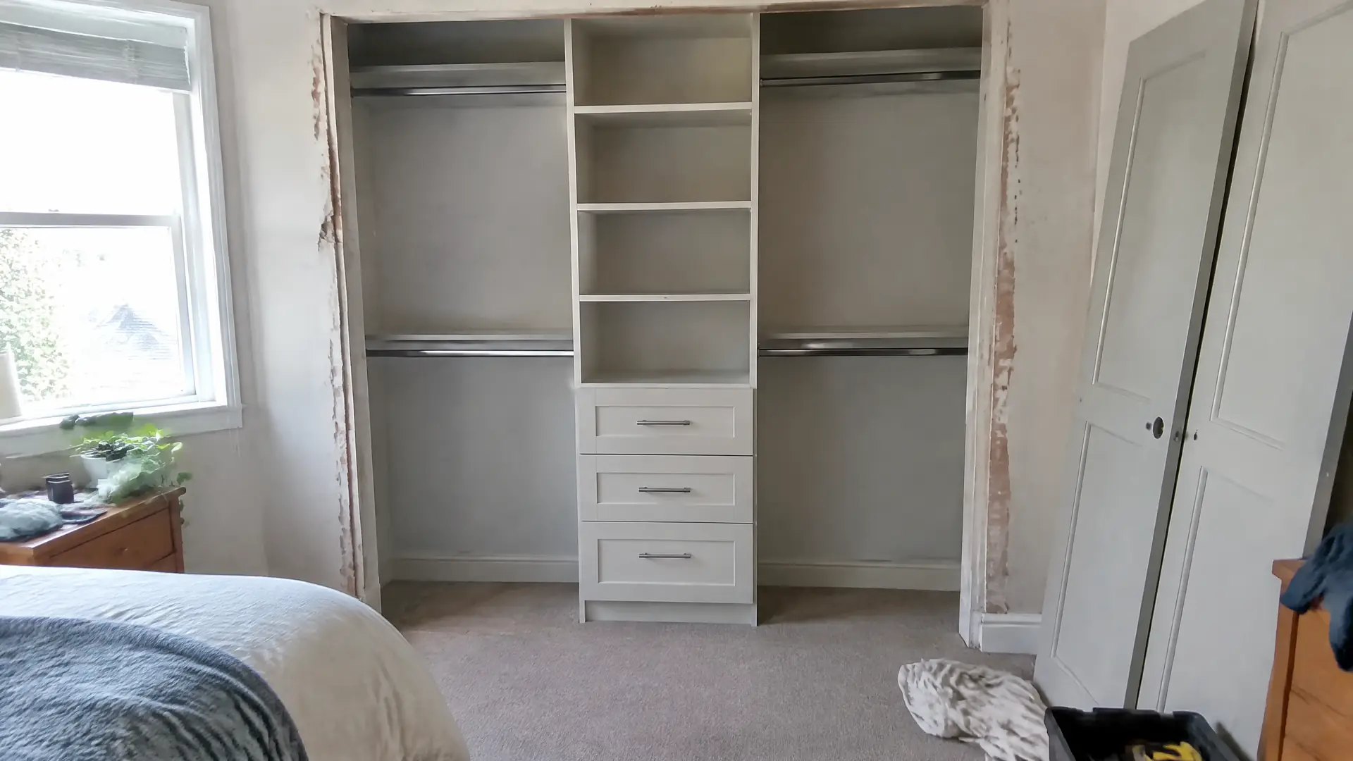 A reach-in bedroom closet fitted with a double rail, adjustable shelves and three drawers