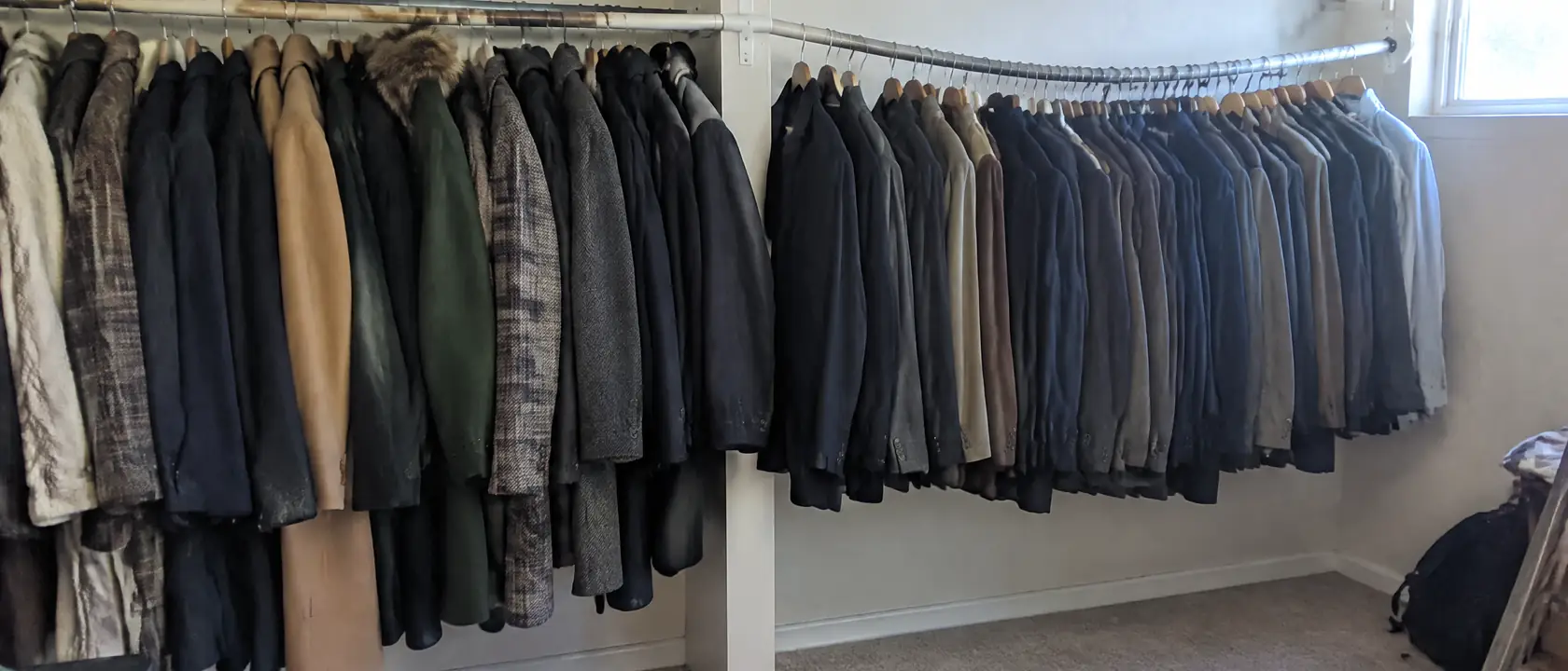 Closet rail of heavy coats held straight by a center bracket beside an older unsupported rail bowing under suits