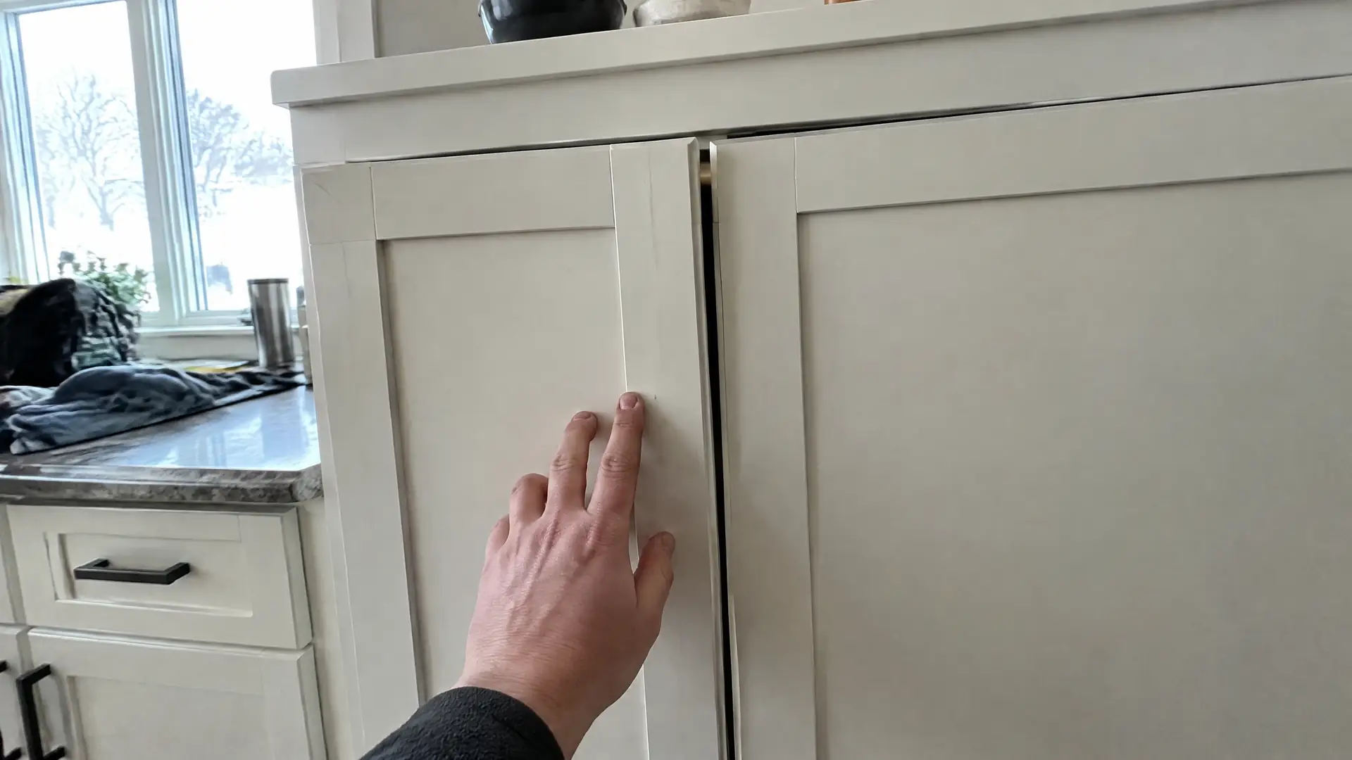 A pair of cabinet doors cupped away from the frame so the gap runs wide at one corner